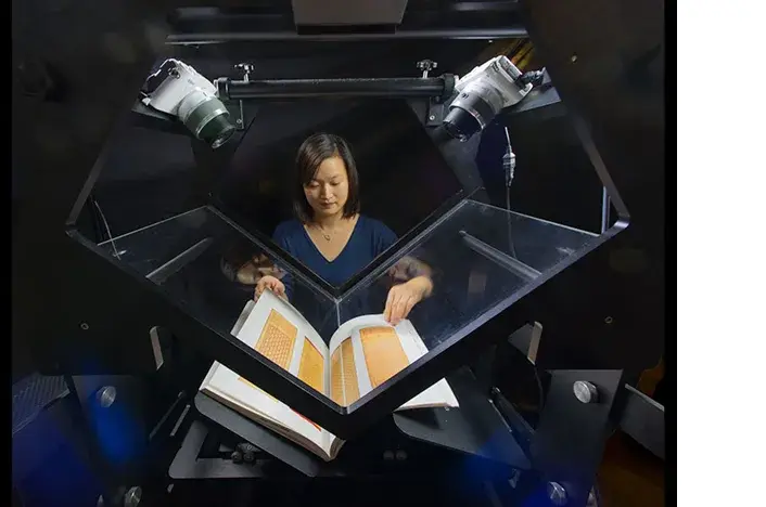 An operator uses a V-shaped Table Top Scribe to digitise a bound book