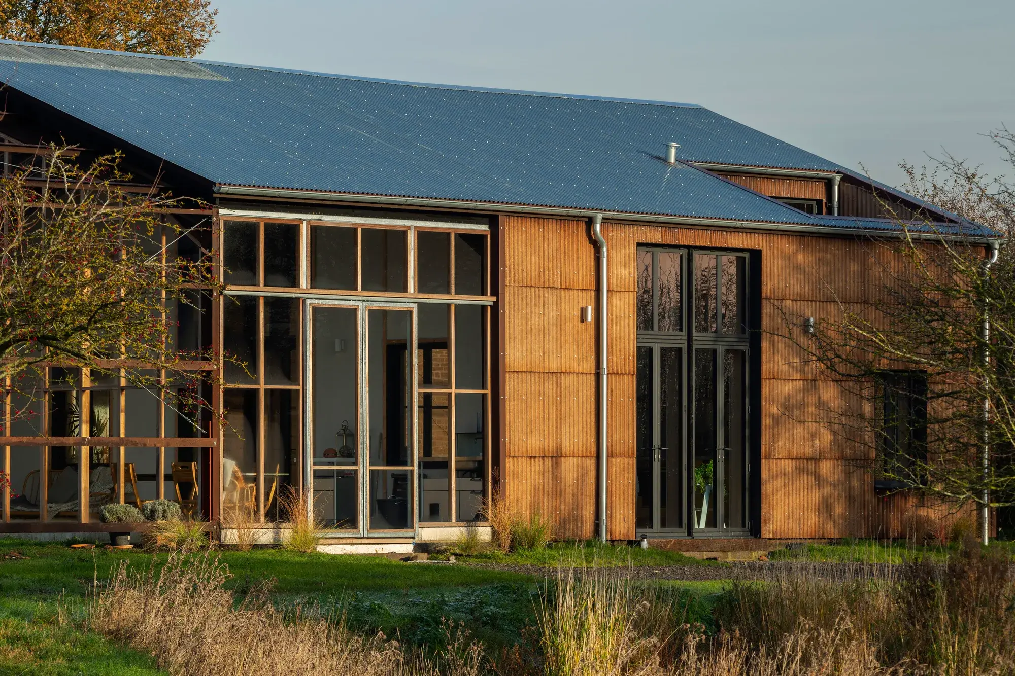 Entrée de la Flat House, bardage ondulé en fibres de chanvre et menuiseries bois