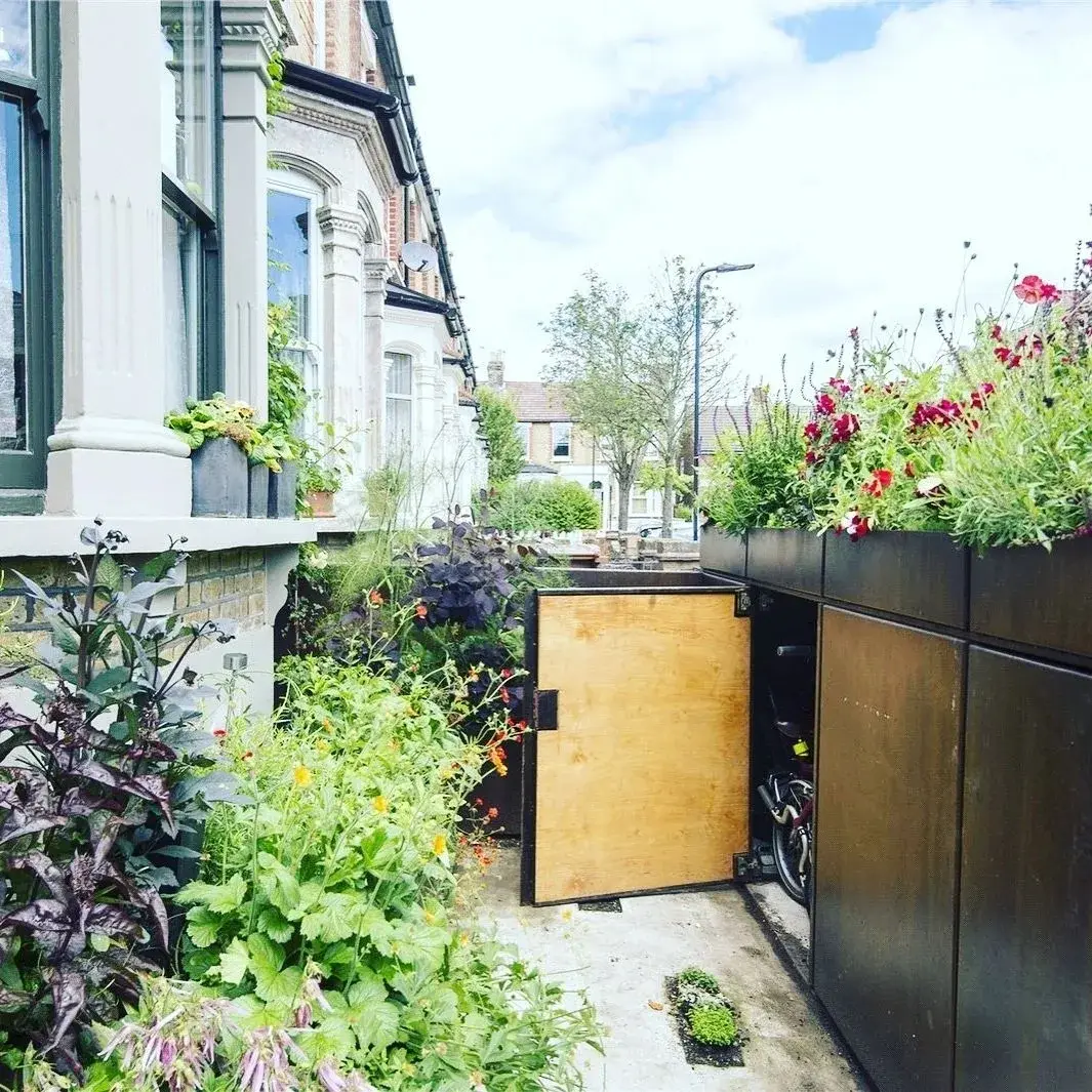 BikeBox en acier oxydé intégré dans un jardin avant londonien avec plantation au-dessus du rangement à vélos