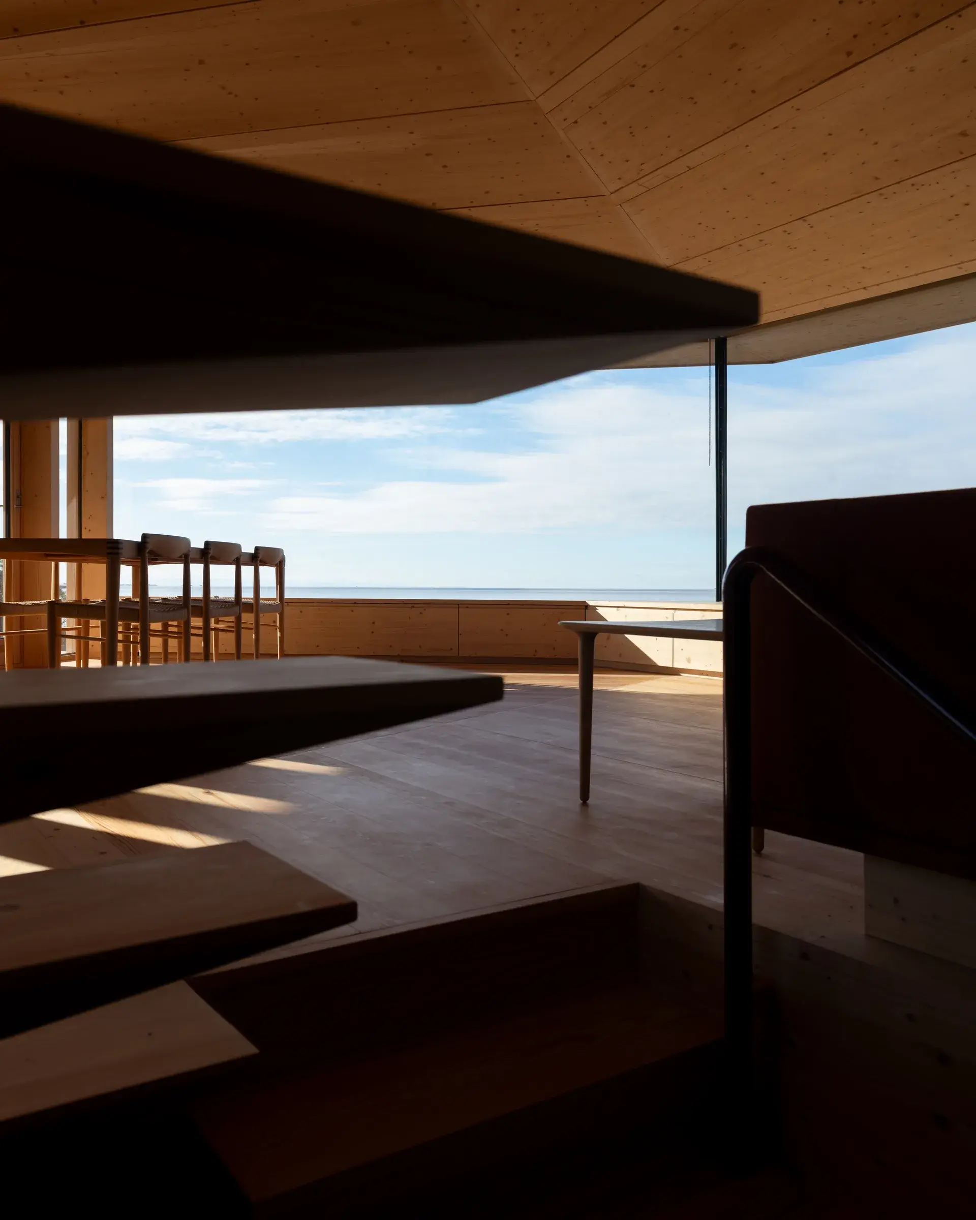 Interior where the timber structure extends into built-in shelves and benches