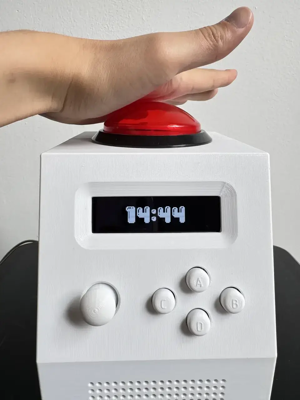 A hand hitting the 100 mm arcade dome on top of CinderClock