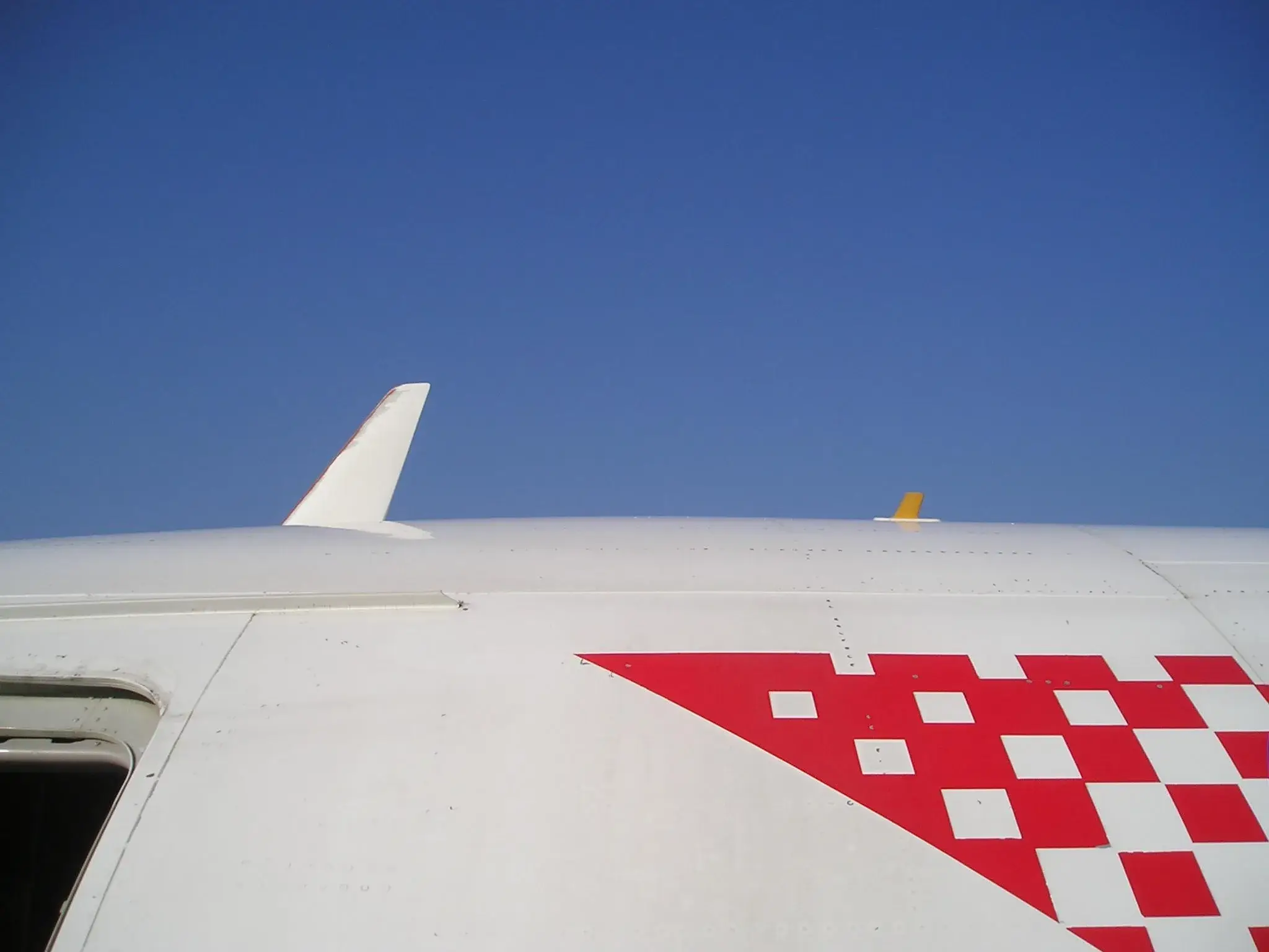 Two fuselage antennas visible on top of an Airbus A319: a white VHF blade and a small yellow fin