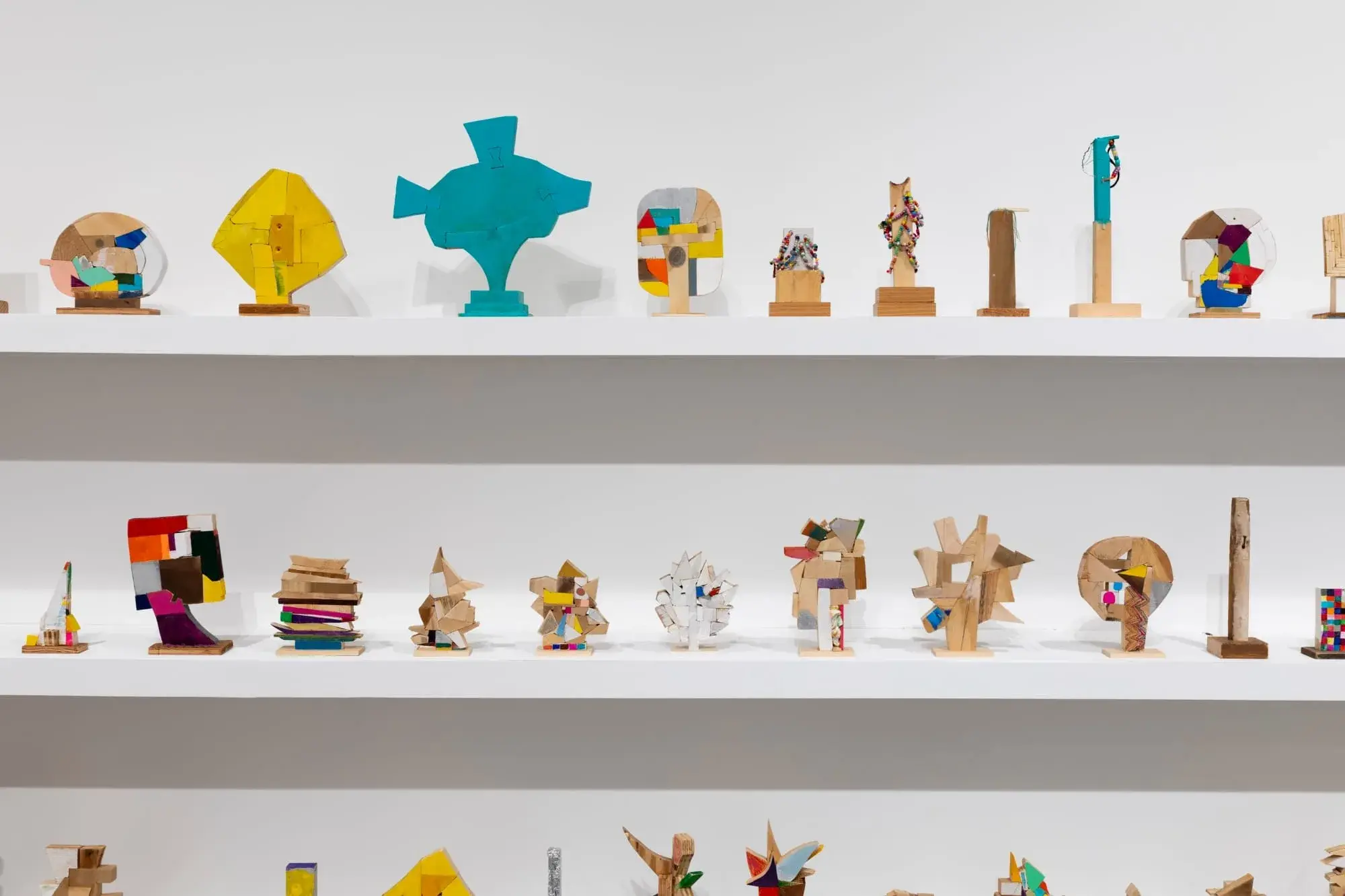 Des centaines de petites sculptures en bois de Damien Hoar de Galvan alignées sur de longues étagères