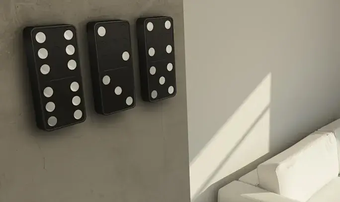 Three large black dominoes with white dots mounted on a concrete wall