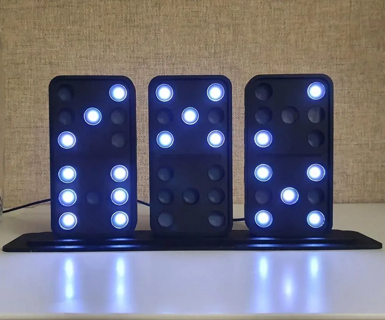 Three black domino tiles on a base showing 9:53 in glowing blue dots
