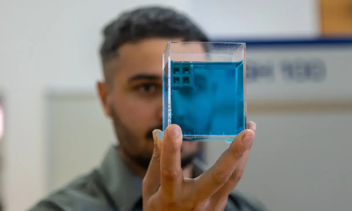 Jordan Noronha tient un petit cube de réseau en titane imprimé en 3D