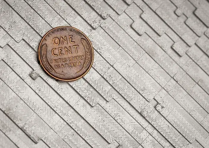 Close-up of a FlowForm tile next to a US penny showing the scale of its surface pattern