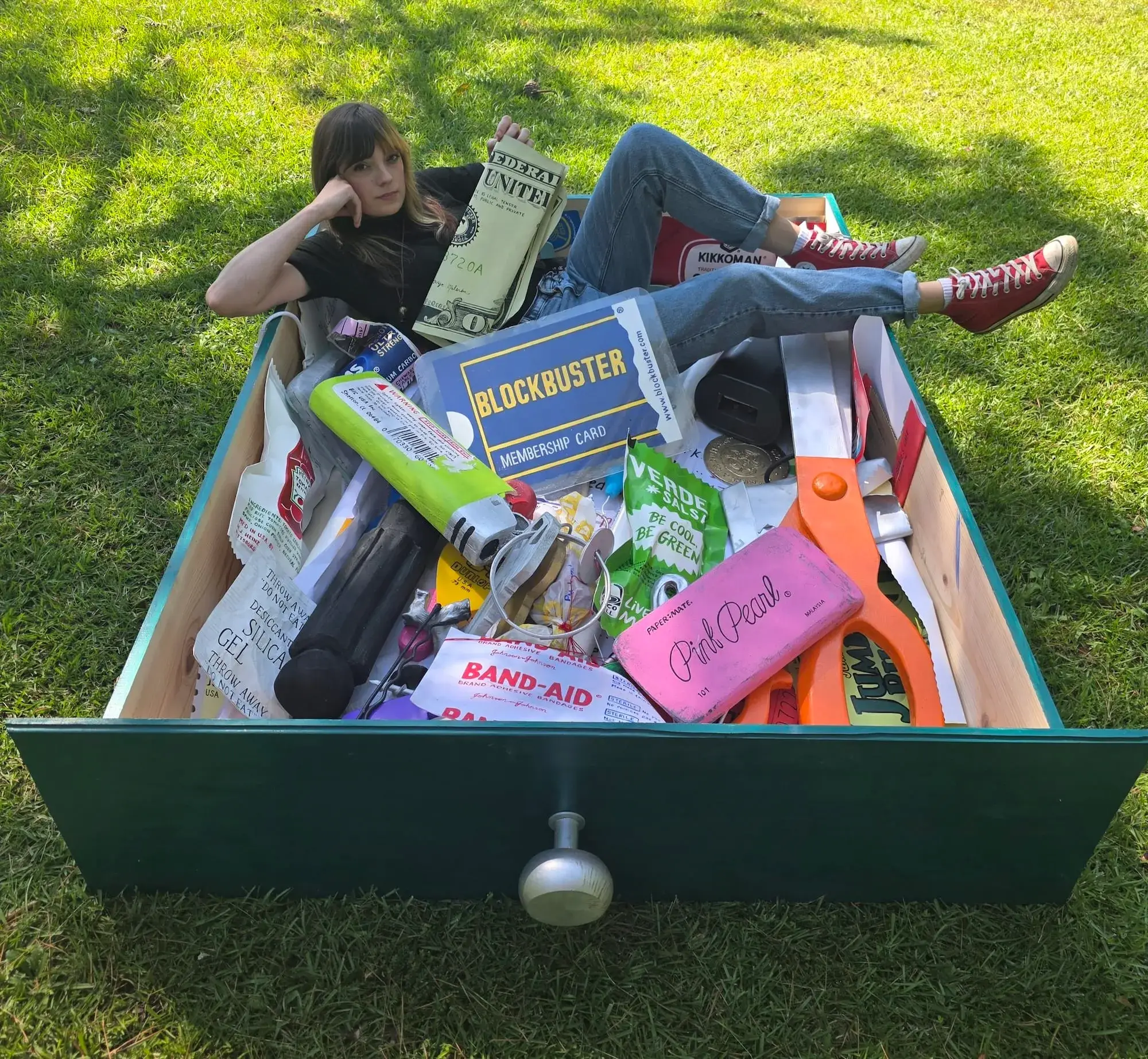 Grace Baldwin reclining inside her sculpture of a giant junk drawer filled with ordinary objects handmade at monumental scale