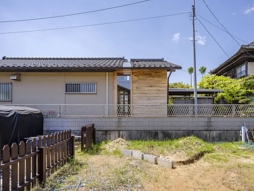 Small timber tea room opening onto a garden in Ichihara through a large glazed wall