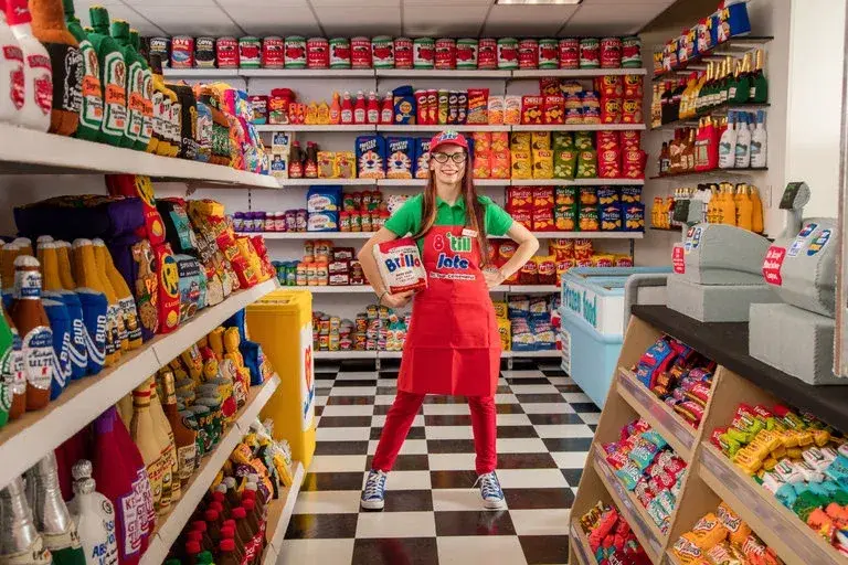 Lucy Sparrow au milieu d’étagères remplies de produits de supermarché recréés en feutre