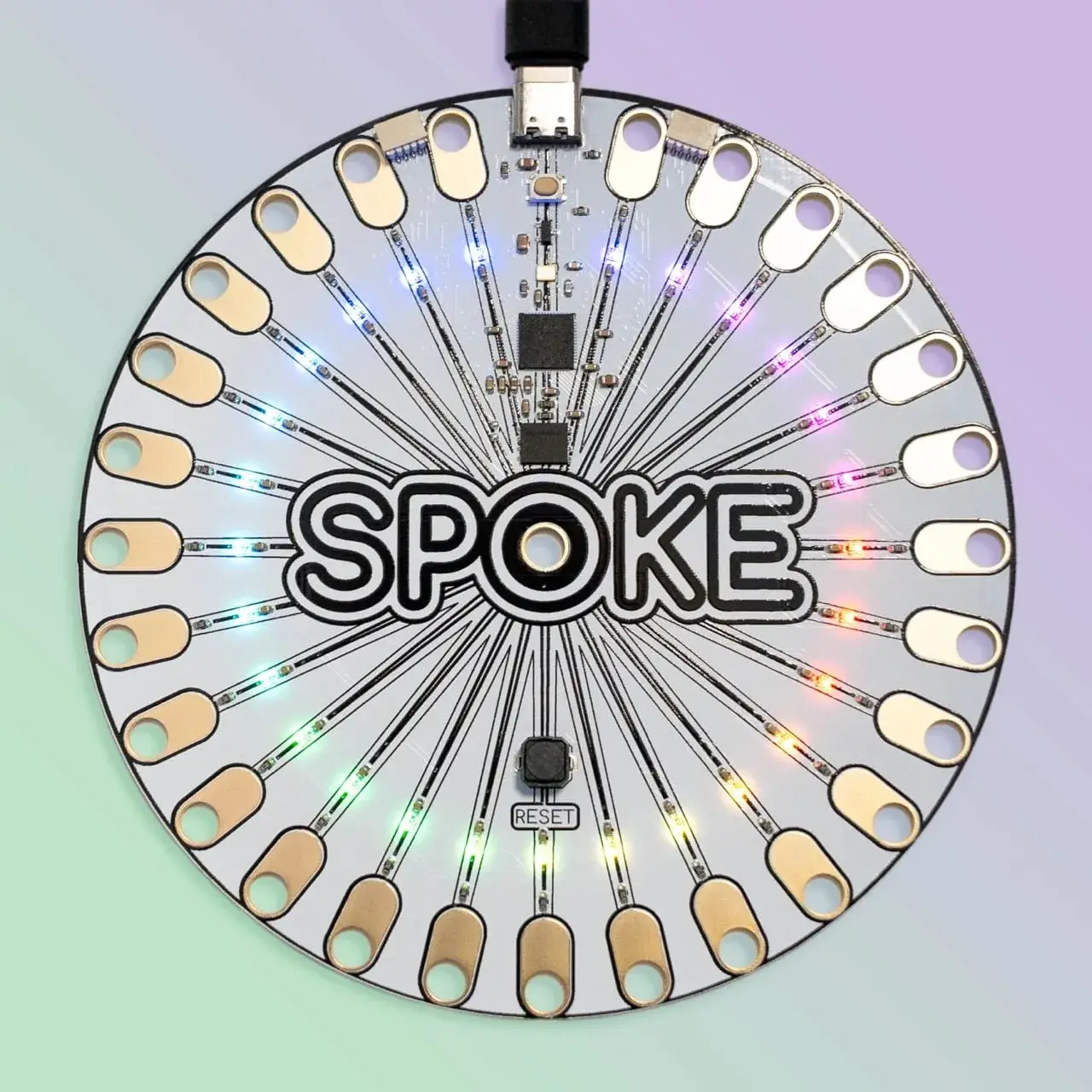 The SPOKE controller, a round circuit board with 27 drilled copper pads and lit NeoPixels