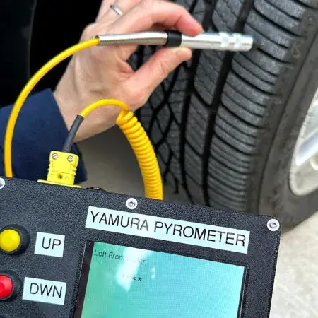 Une main plante la sonde du pyromètre Yamura dans la bande de roulement d'un pneu