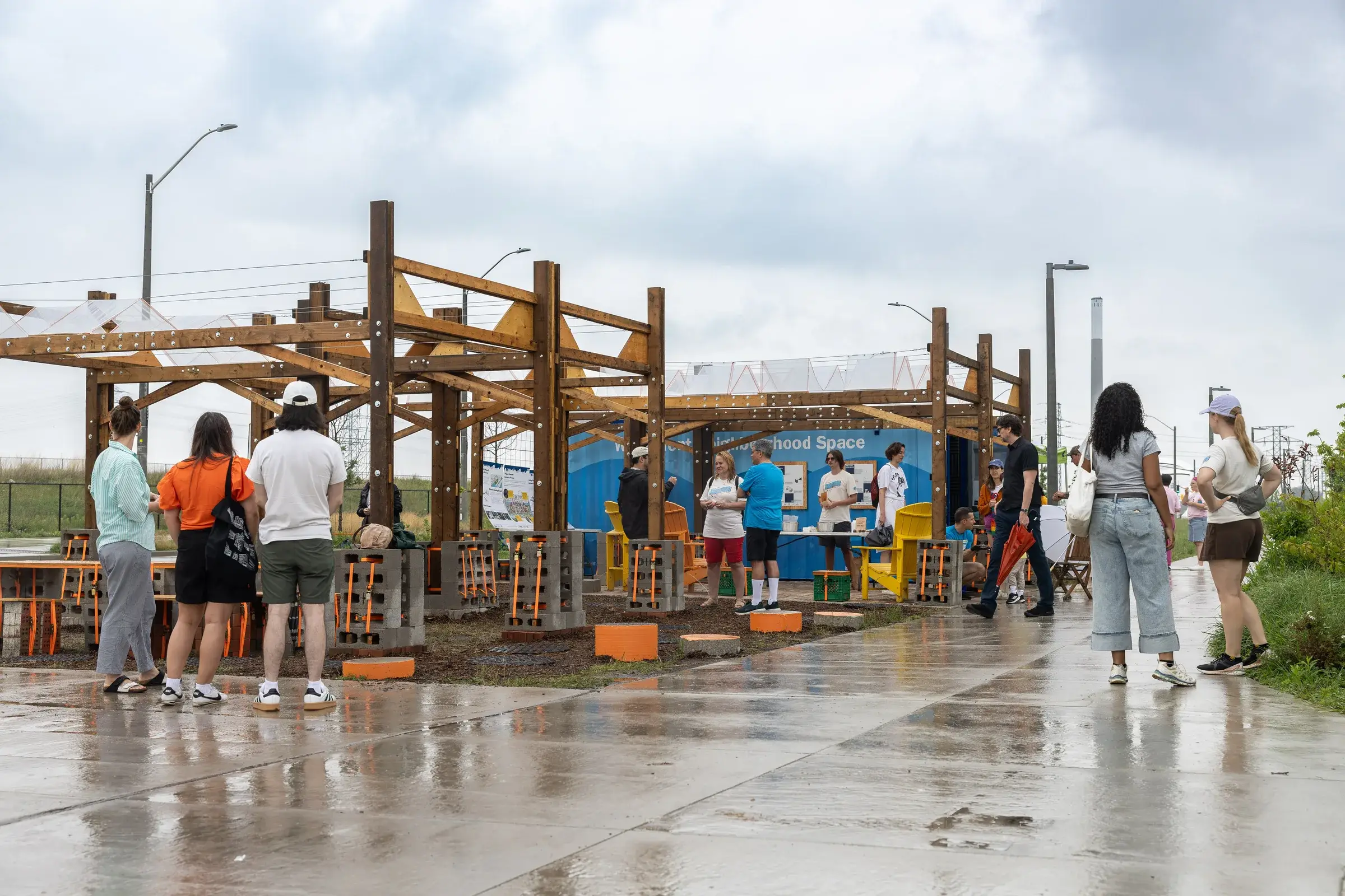 Visiteurs dans le Waterfront Neighbourhood Space à Toronto, sous une structure temporaire en bois et matériaux récupérés