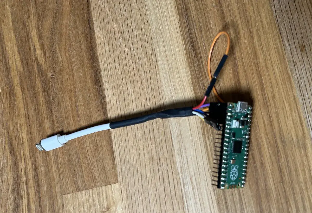 A Raspberry Pi Pico 2 with the cut end of a white Apple Lightning cable soldered to its pins